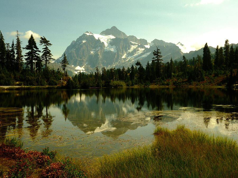 Mountain ridges and autumn trees mirrored in still water.