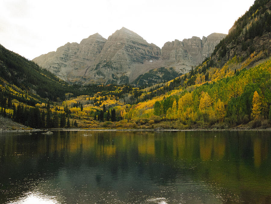 Mountain peaks and golden autumn slopes reflected in a still lake.