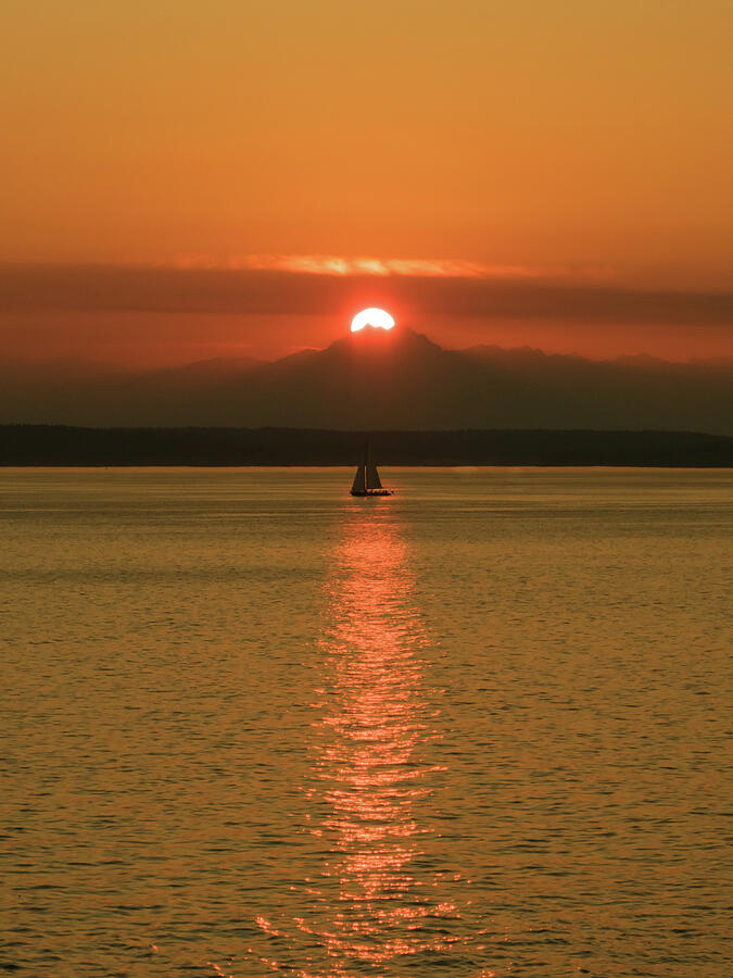 A small sailboat on open water beneath a warm evening sky.