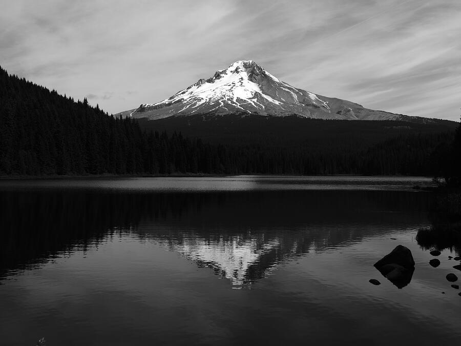 A snow-capped mountain mirrored in still water, photographed in black and white.